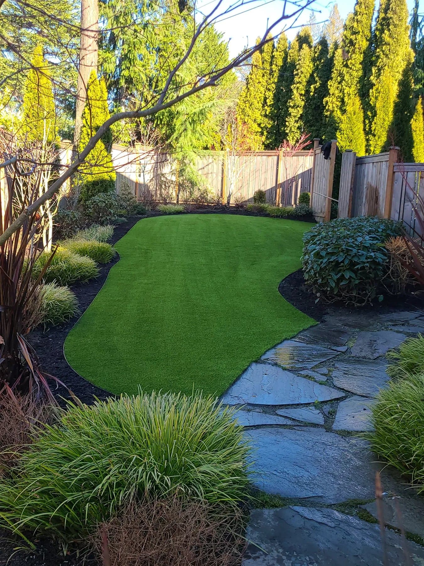Backyard putting green beside a stone garden path and landscaped planting beds