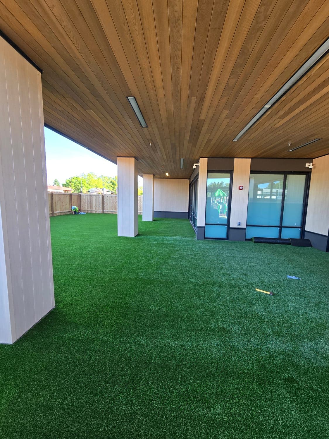 Modern covered patio and entry finished with low-maintenance artificial turf